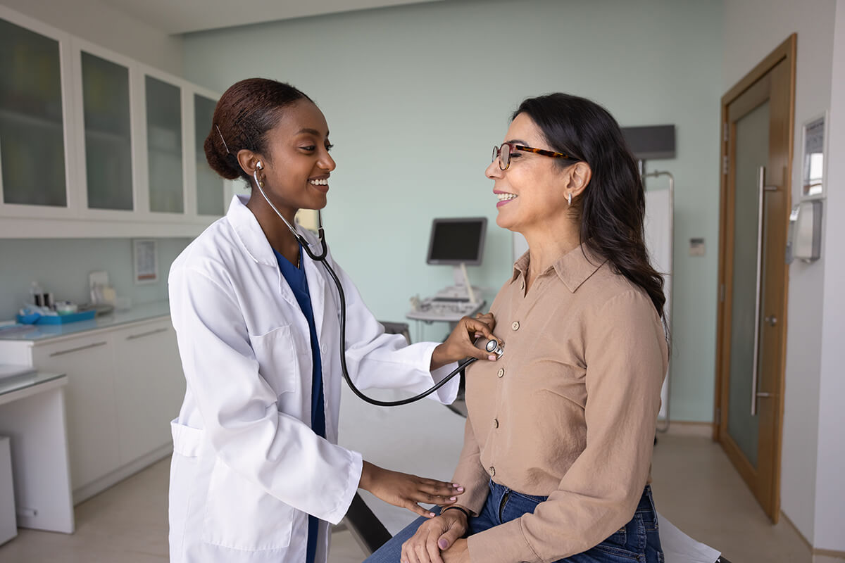 Doctor performing a routine medical exam on a patient, representing early diagnosis, ongoing care, and critical illness insurance protection.