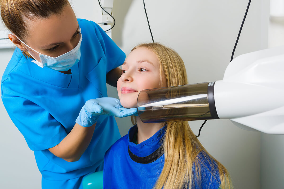 Dental professional performing a routine dental examination on a young patient, representing preventive care and affordable dental coverage.